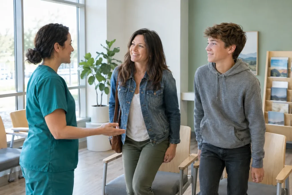 Clinician greeting a mother and her teenage son in a bright, modern urgent care waiting area